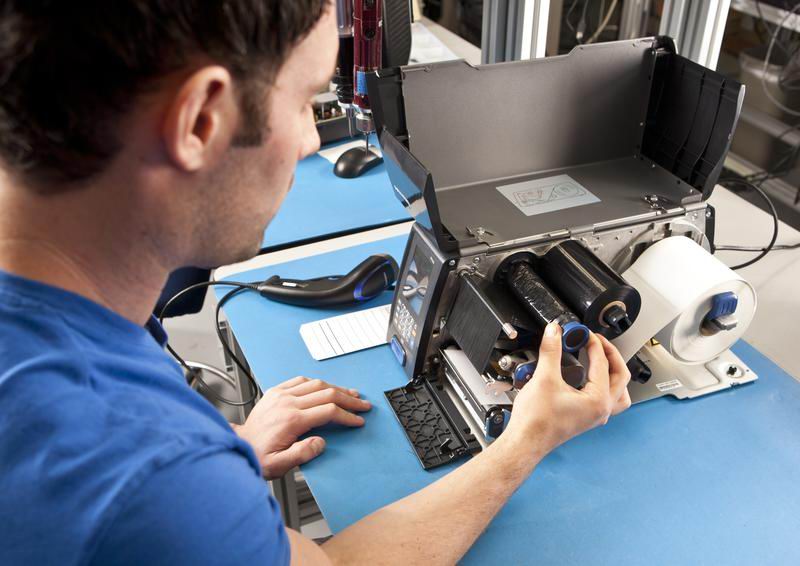 Operario revisando los cabezales de una impresora de etiquetas